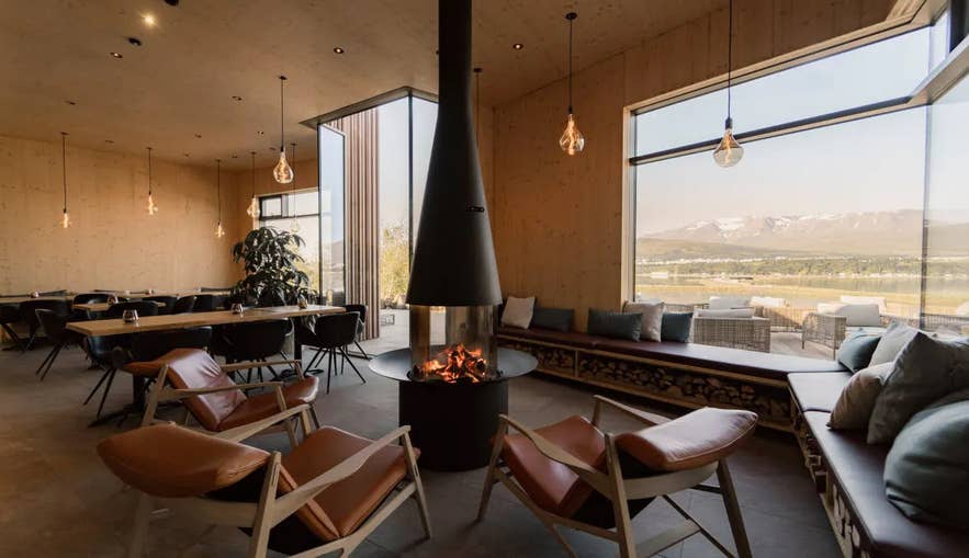 Der mit Holz verkleidete Speisesaal des Bistros der Forest Lagoon mit Kamin und Fensterausblick auf den Fjord