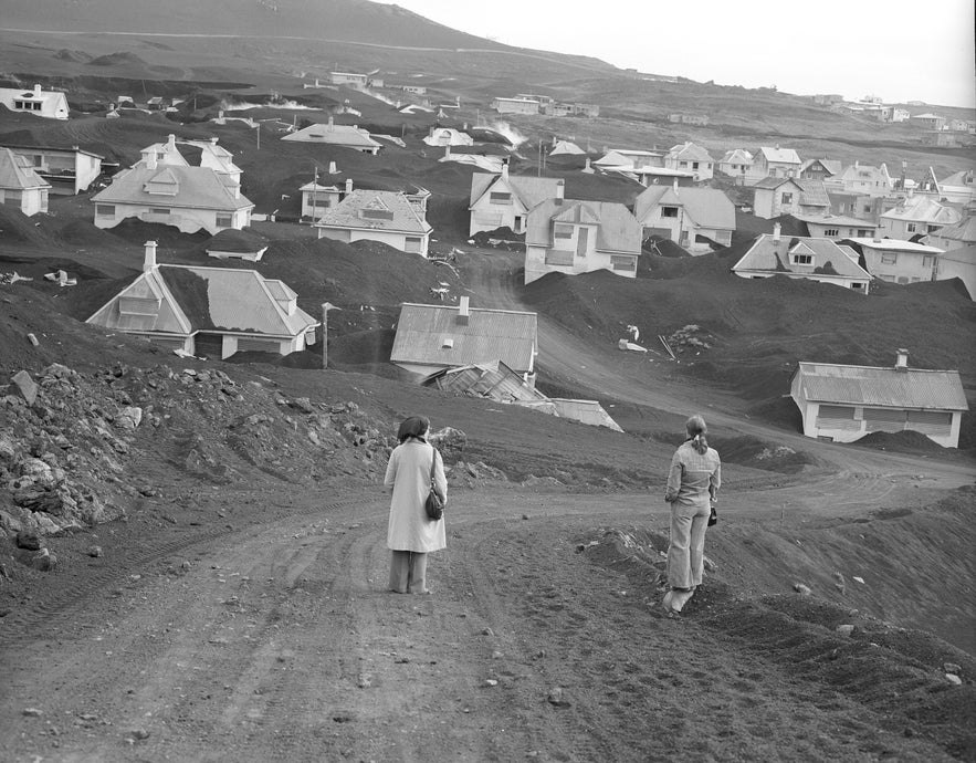 Two people look over the devastation of the volcanic eruption of Eldfell on the island of Heimaey