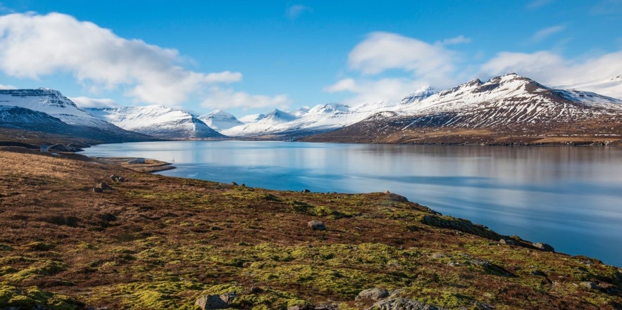 The best places to visit in East Iceland include the beautiful mountains of Faskrudsfjordur reflecting on the ocean.