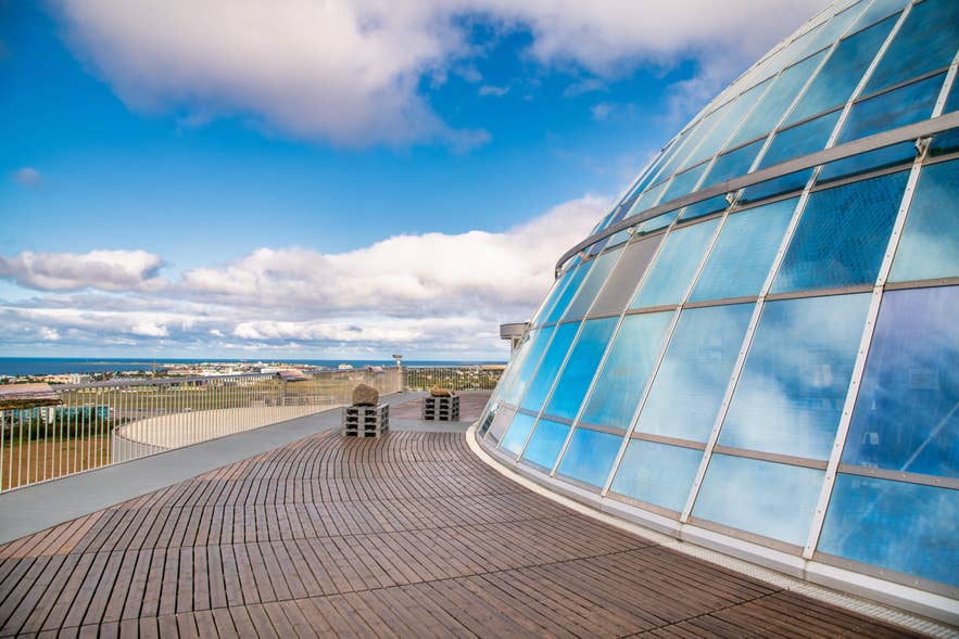 Perlan’s glass dome reflects the sky as a viewing deck overlooks Reykjavik and the distant coastline on a clear day.