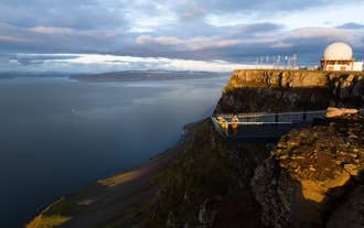 Traveler admiring the view from Bolafjall Sky Walk as the midnight sun sets over the Westfjords of Iceland.