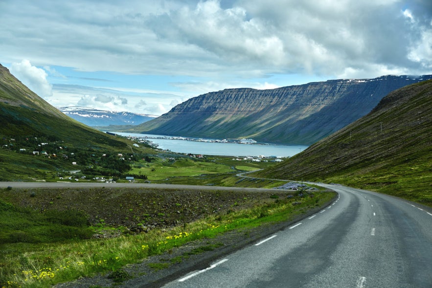 Scenic road overlooking Isafjordur Fjord in the Westfjords, with mountains, green valleys, and coastal views.