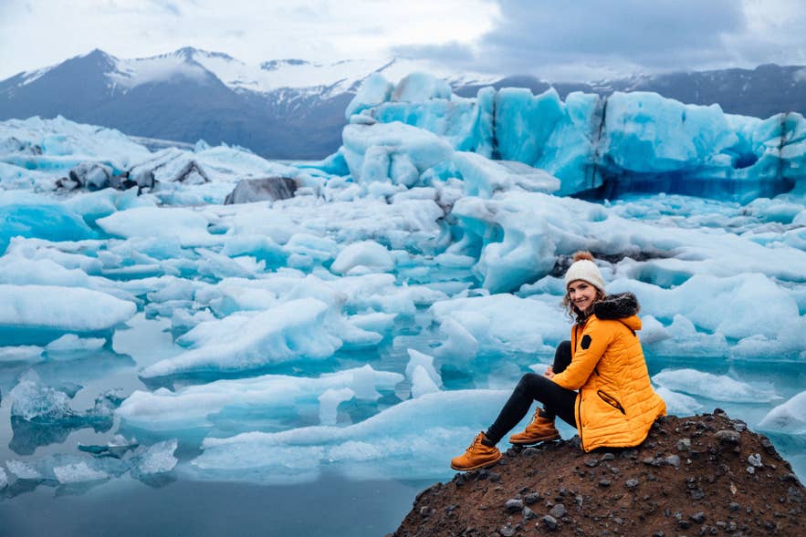 Donna vestita a strati caldi alla laguna glaciale Jokulsarlon, esempio di cosa indossare in Islanda vicino al Vatnajokull.