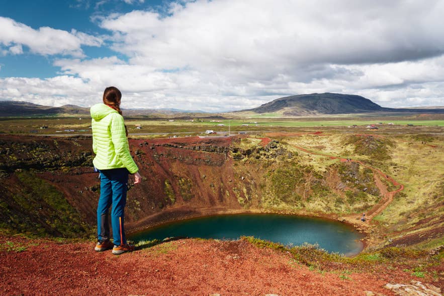 Femme admirant le cratère de Kerid près de Selfoss dans le sud de l’Islande, portant des vêtements d’extérieur illustrant quoi porter en Islande.
