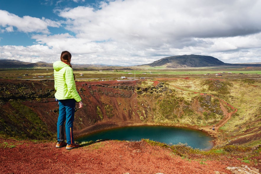 Woman overlooking Kerid Crater near Selfoss in South Iceland, wearing outdoor layers that show what to wear in Iceland.
