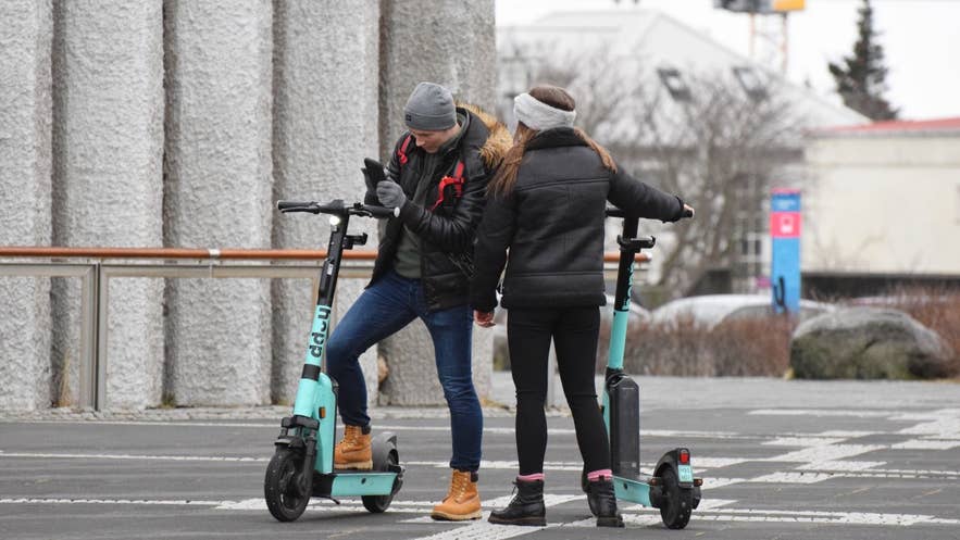 人们在雷克雅未克哈尔格林姆斯大教堂（Hallgrimskirkja）旁使用Hopp应用和Hopp滑板车。