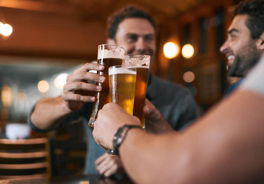 Friends clinking glasses of beer in a cozy bar in Iceland