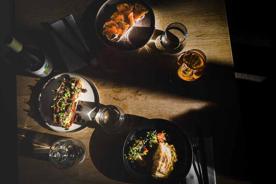 Overhead view of plated dishes and drinks on a wooden table at LYST caf&eacute; in Akureyri.