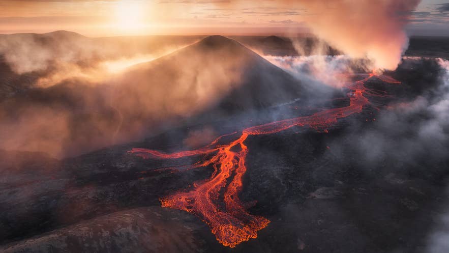 熔岩从冰岛利特利赫鲁图尔火山流出，在日落时分烟雾弥漫的天空下发出炽热光芒。