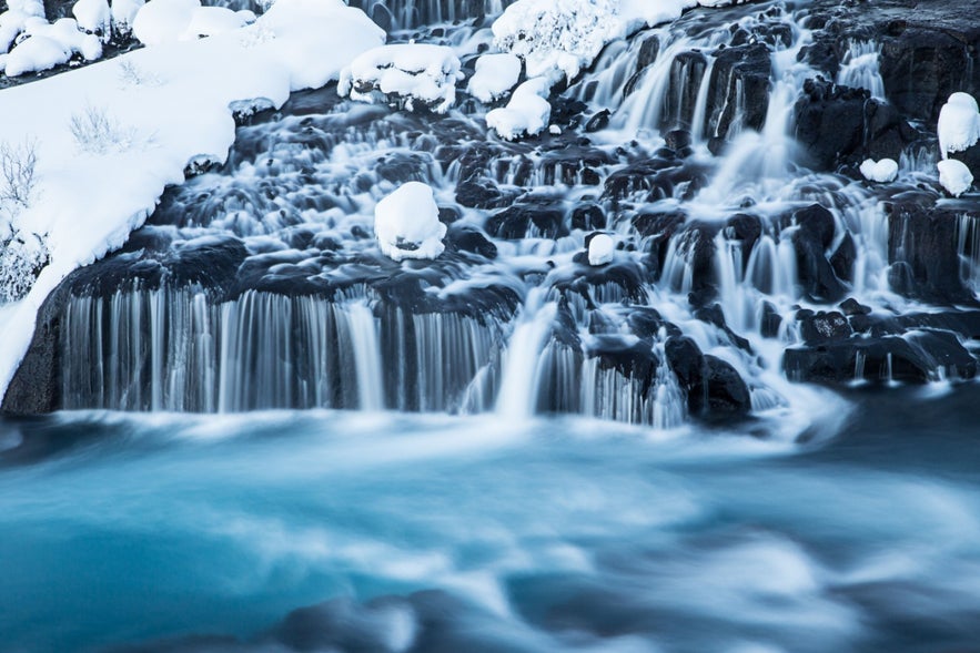 Hraunfossar Waterfalls flowing through lava fields in western Iceland during winter.