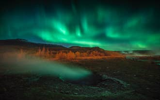 Aurora borealis above a steaming geothermal area along the Golden Circle in Iceland.