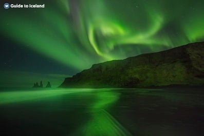 Witness the ethereal Northern Lights gracefully illuminating Reynisfjara Beach in all its splendor.