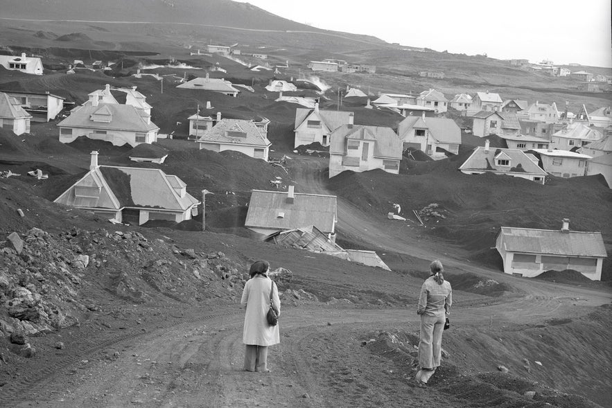 Two women overlook houses buried in volcanic ash after the 1973 Eldfell eruption in Heimaey, Westman Islands, Iceland.
