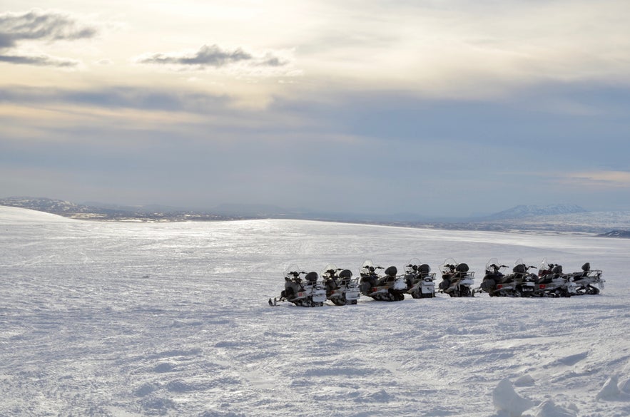 Snowmobiles are lined up on deep snow on Langjokull Glacier 