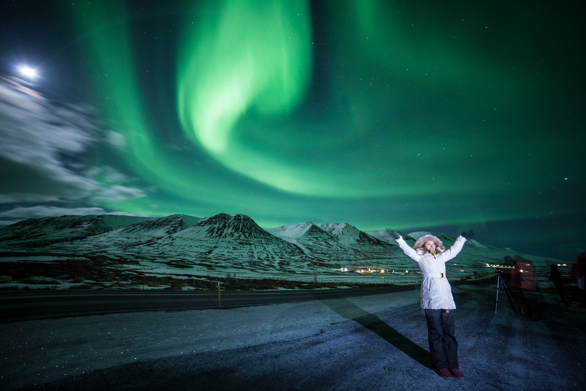 Winter landscape in North Iceland with a traveler admiring the northern lights.