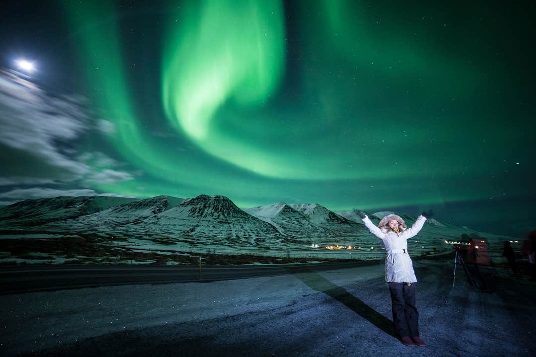 Paysage hivernal du nord de l'Islande avec un voyageur admirant les aurores boréales.