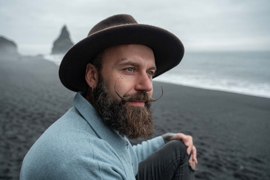 Man sitting on Reynisfjara black sand beach near Vik, Iceland