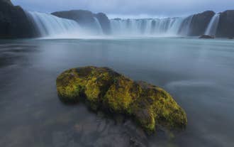 Misty cascades of Godafoss Waterfall on a cloudy day during a North Iceland tour.