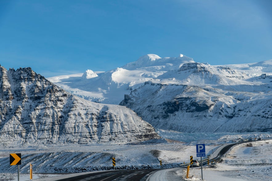 Winter road in Iceland with snowy mountains and glacier landscape, a scenic drive through the Icelandic Highlands.