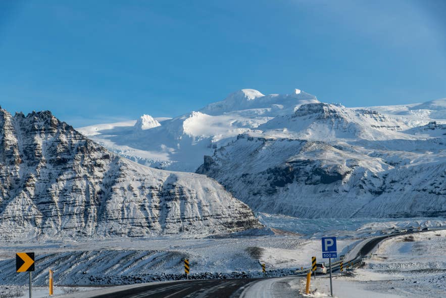 Winter road in Iceland with snowy mountains and glacier landscape, a scenic drive through the Icelandic Highlands.