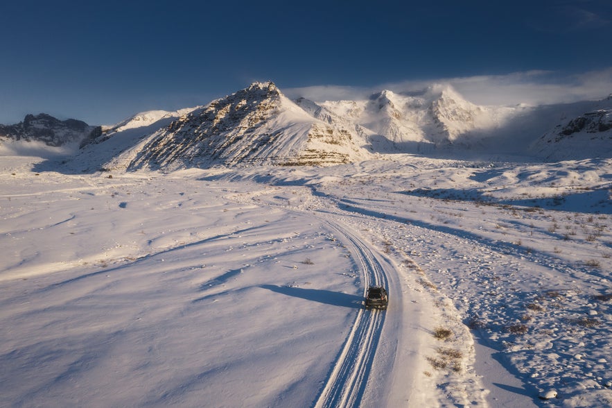 Car driving on a snowy mountain road in Iceland during winter driving conditions.