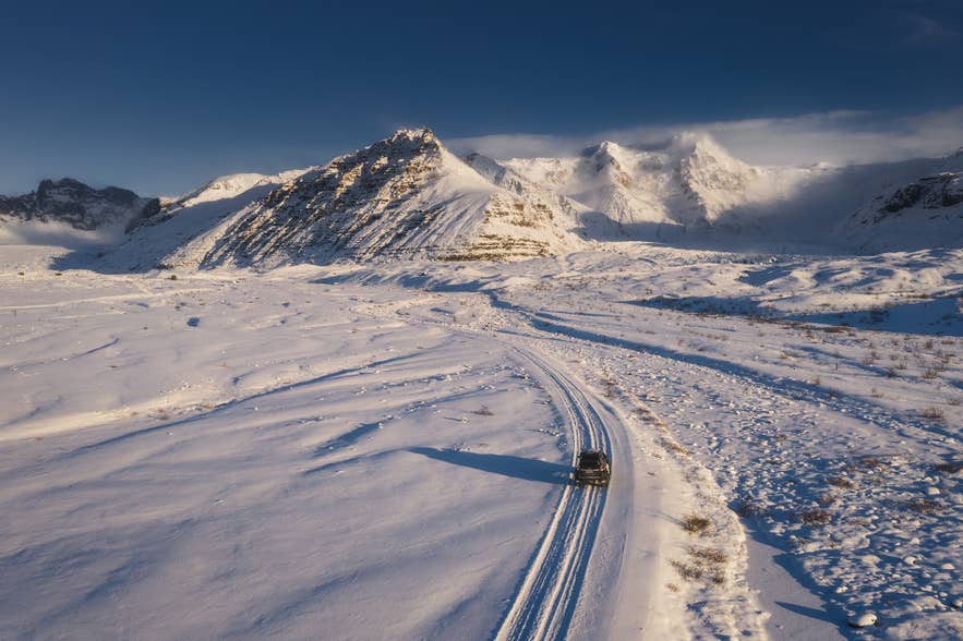 Car driving along a snowy Icelandic road in winter.