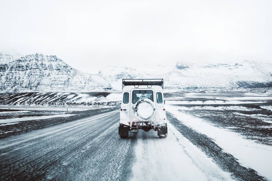 4x4 vehicle driving along a snow-covered road in Iceland during winter.