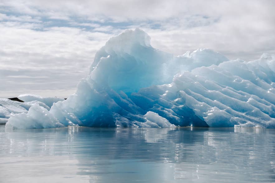 Large blue and white iceberg floating on the calm water of Fjallsarlon Glacier Lagoon