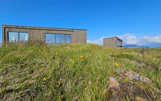 Exterior view of Hitarneskot Accommodation surrounded by grassy hills in West Iceland.