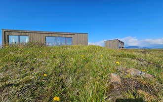 Exterior view of Hitarneskot Accommodation surrounded by grassy hills in West Iceland.