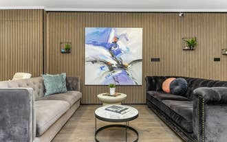 A big painting is hanging on wooden wall at Flyers Airport Hotel's lounge.