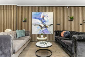 A big painting is hanging on wooden wall at Flyers Airport Hotel's lounge.