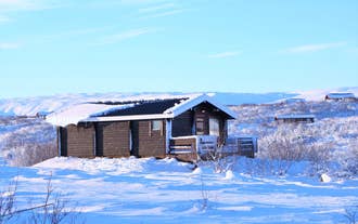 Snow-covered cabin surrounded by wintry Icelandic landscape at Uthlid Cottages.