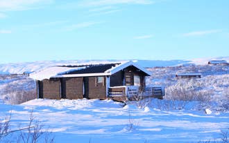 Snow-covered cabin surrounded by wintry Icelandic landscape at Uthlid Cottages.