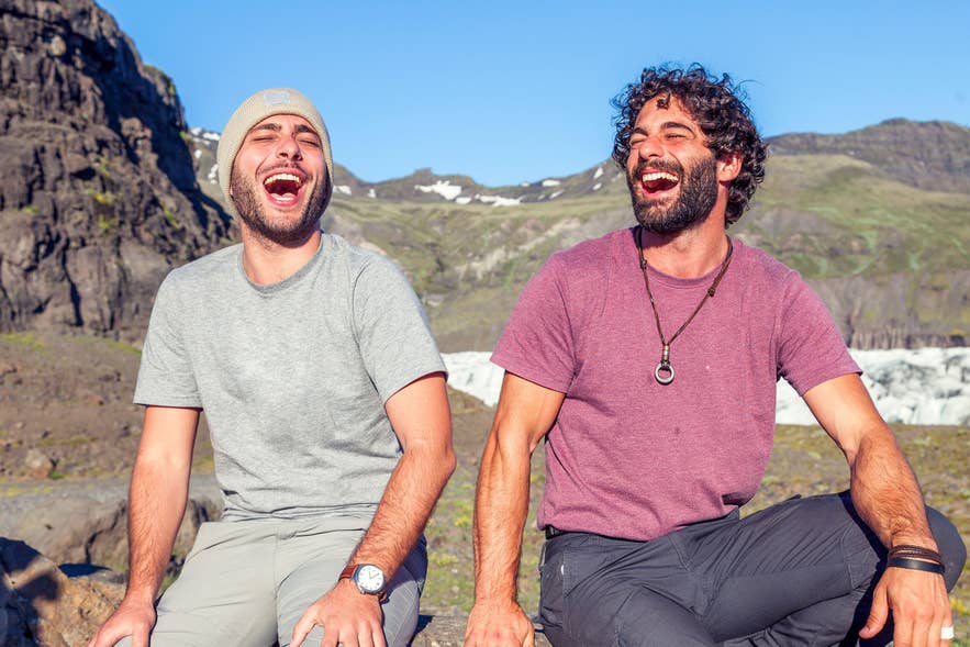 Two people sitting on rocky terrain with Iceland mountains and glaciers in the background
