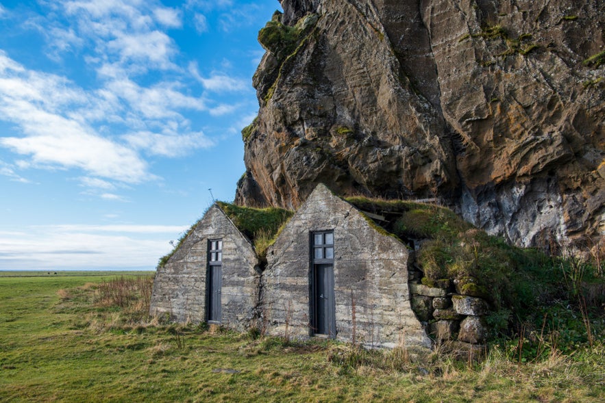 Drangurinn Rock Formation near Hvolsvollur, South Iceland, turf-roofed stone shelters beneath coastal cliffs on the South Coast.