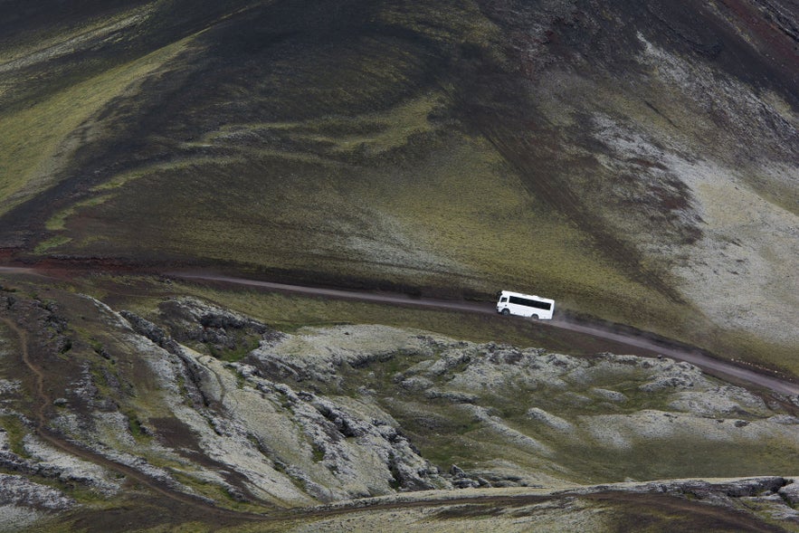 Tour bus on mountain road near Hvolsvollur, South Iceland, driving through rugged highland landscape on the South Coast.