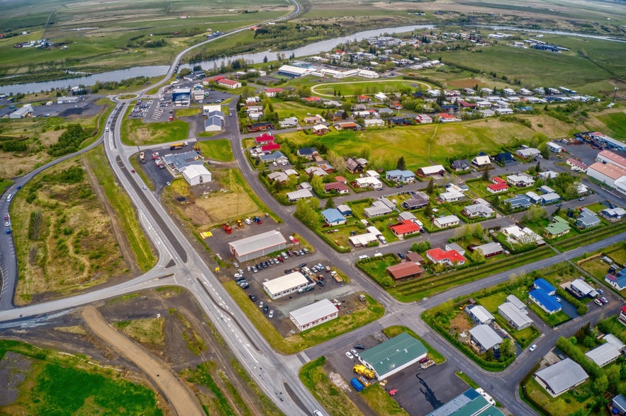 Aerial view of Hella in South Iceland, showing residential neighborhoods, main roads, riverbanks, and surrounding farmland.