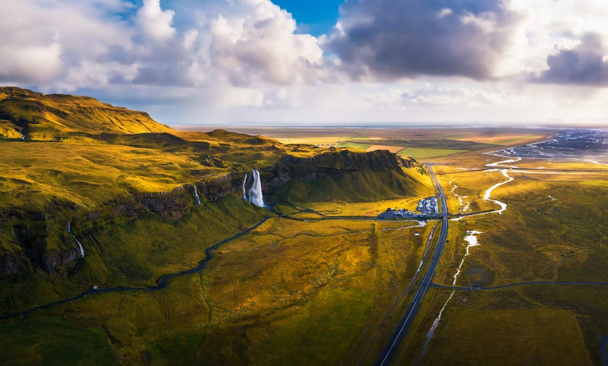 Seljalandsfoss Waterfall seen near the Ring Road, surrounded by golden fields in South Iceland.