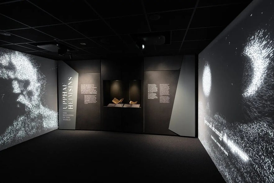 Exhibition space at World in Words showing illuminated text panels and manuscripts in a dark gallery setting.