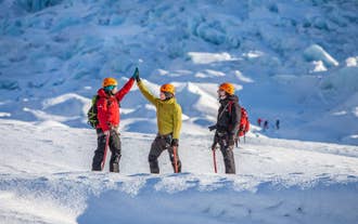 Group of hikers exploring the ice formations of Solheimajokull Glacier during a guided glacier hike in South Iceland.