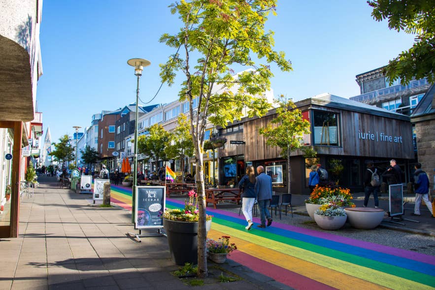 Skolavordustigur Rainbow Street in Reykjavik with shops, cafes, pedestrians, and colorful pavement leading through the city center.