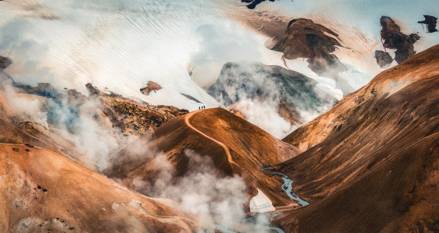 Kerlingarfjoll mountains in Icelandic Highlands, with geothermal steam, colorful rhyolite hills, and winding hiking trail