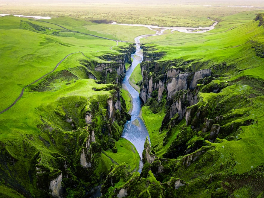Aerial view of Fjadrargljufur Canyon near Kirkjubaejarklaustur in South Iceland, showing the winding Fjadra River and green cliffs.