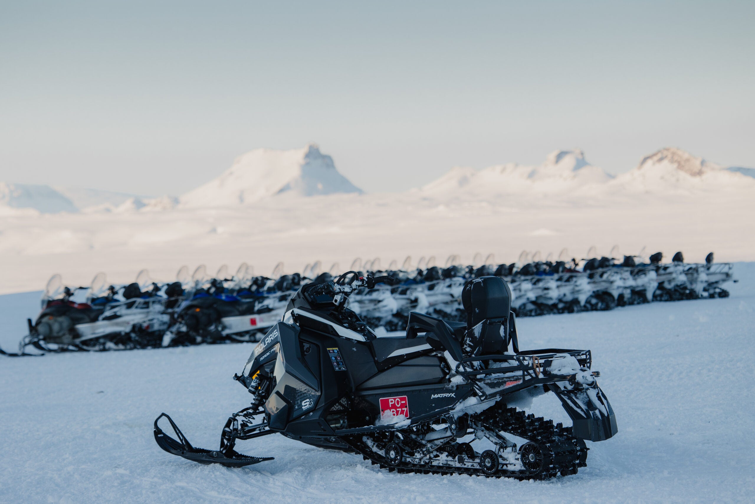 A snowmobile stands on a vast plain of snow, ready for a Langjokull snowmobiling tour.