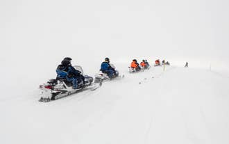 Group riding snowmobiles on Langjokull Glacier in heavy snow, part of the thrilling glacier adventure experience in Iceland.