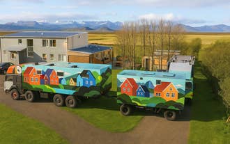 Exterior view of Truck Inn by Ourhotels in Borgarfjordur, featuring colorful restored army trucks set in the countryside.