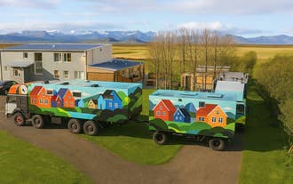 Exterior view of Truck Inn by Ourhotels in Borgarfjordur, featuring colorful restored army trucks set in the countryside.