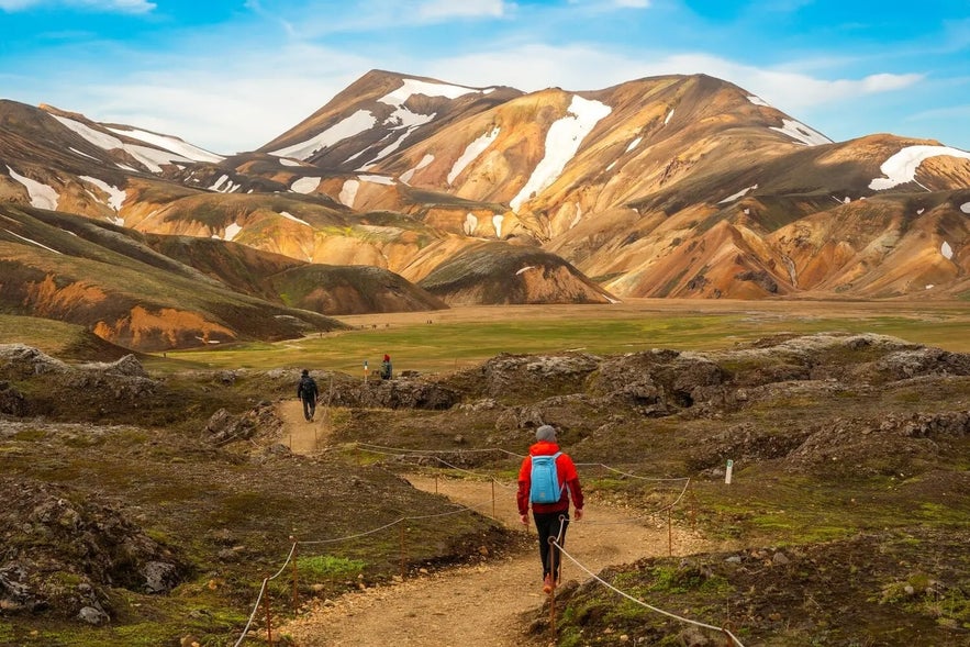Hikers walking along a marked trail in the colorful mountains of Landmannalaugar.