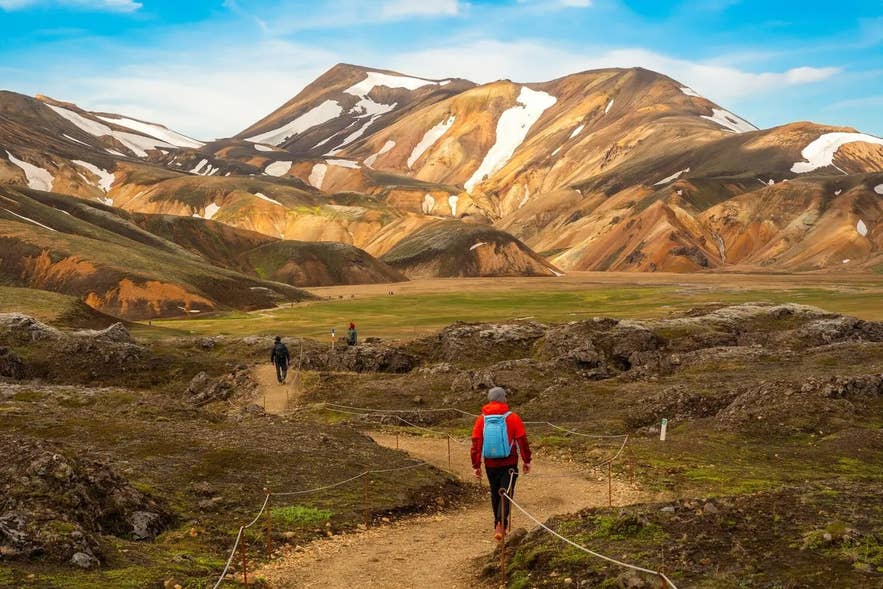 Hikers walking along a marked trail in the colorful mountains of Landmannalaugar. Hikers walking along a marked trail in the colorful mountains of Landmannalaugar.